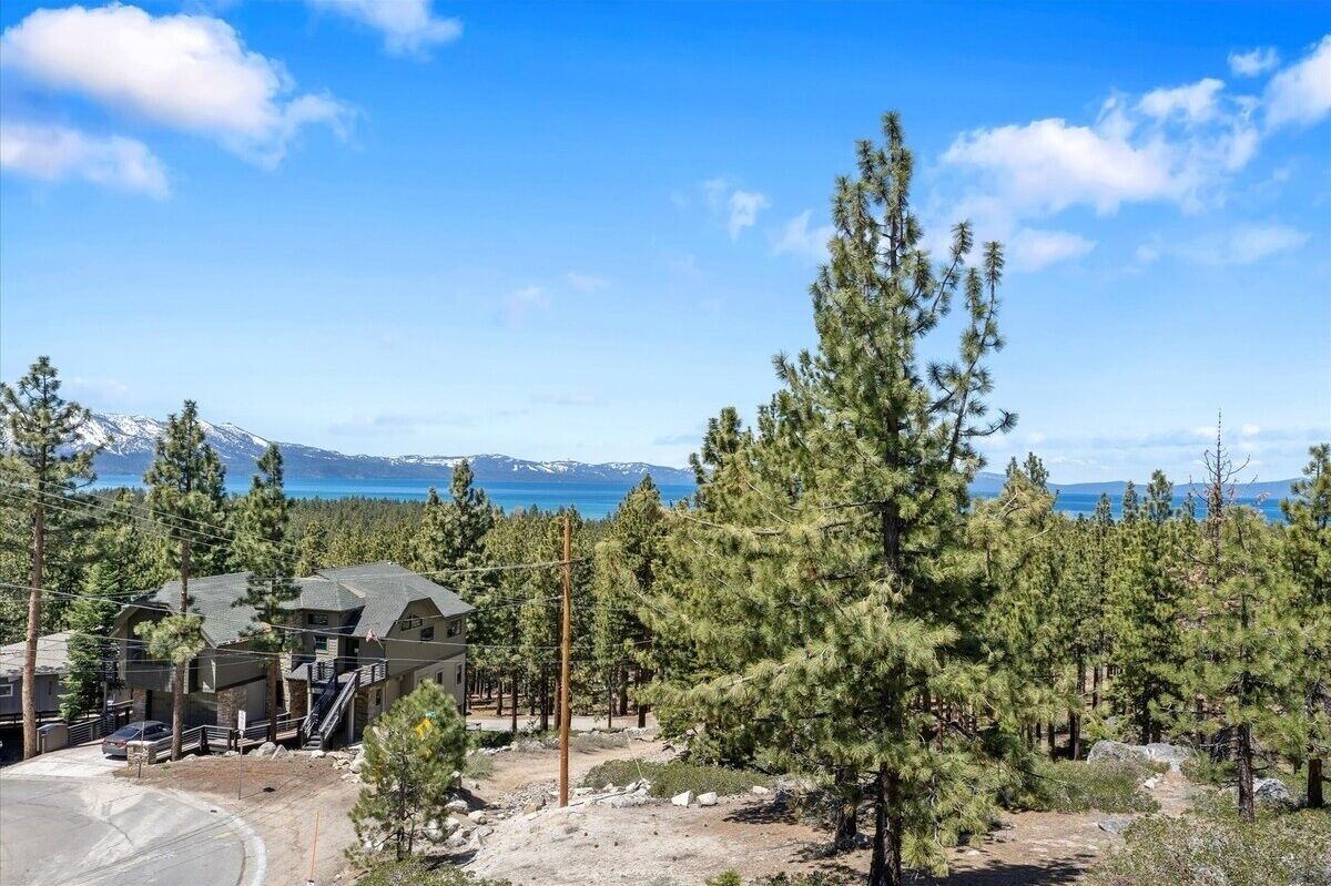 A lodge with a mountain view, surrounded by pine trees, and a clear sky.