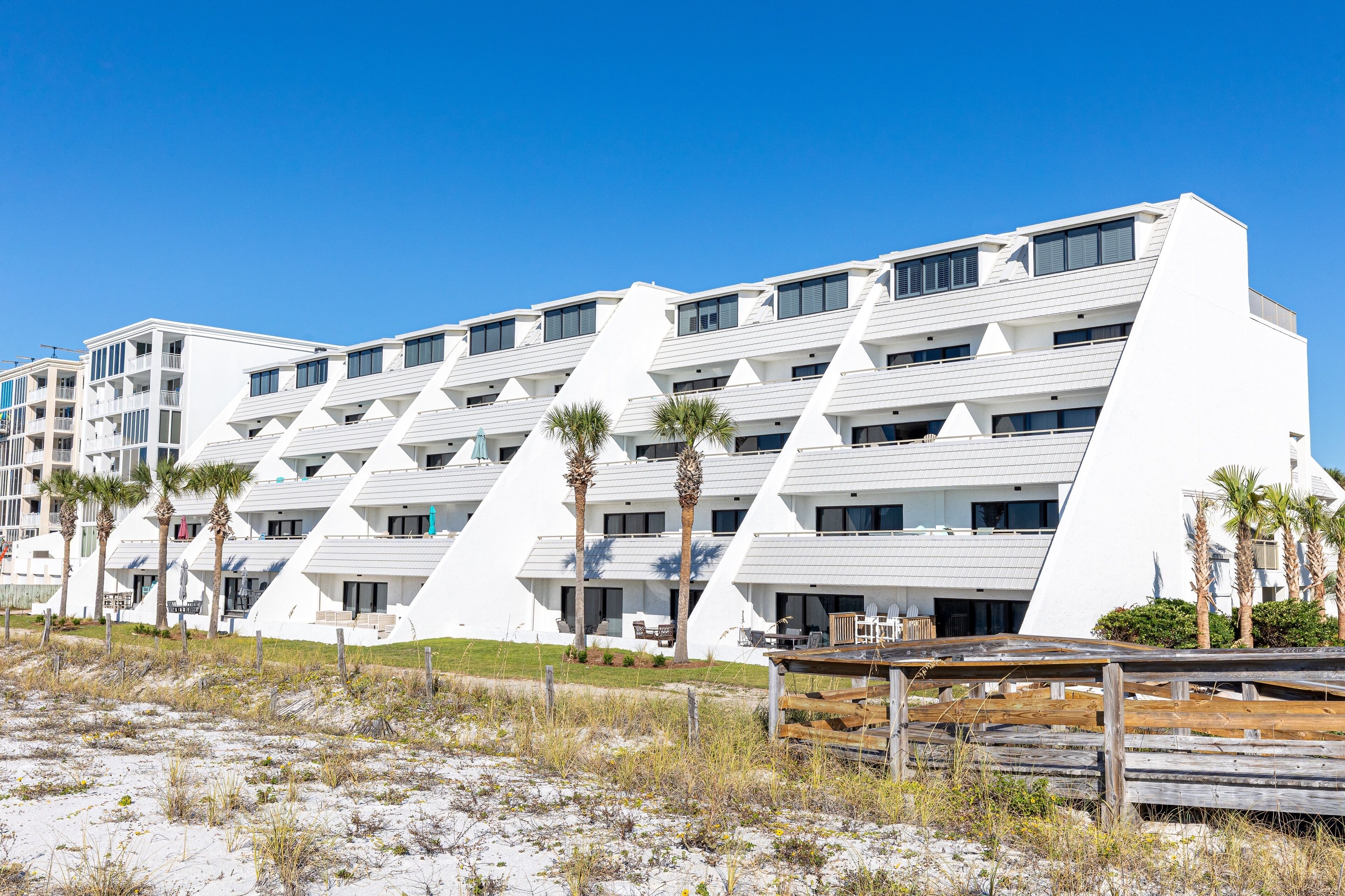 Un hotel moderno con un diseño geométrico único, que cuenta con varios balcones y ubicación frente a la playa.