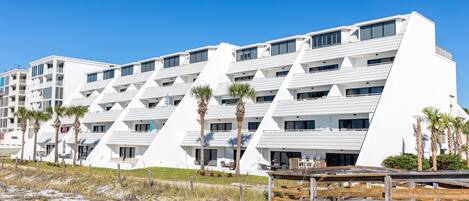 Un hotel moderno con un diseño geométrico único, que cuenta con varios balcones y ubicación frente a la playa.