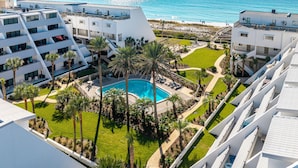 Ein modernes Hotel mit Pool, umgeben von Palmen und Blick auf den Ozean.