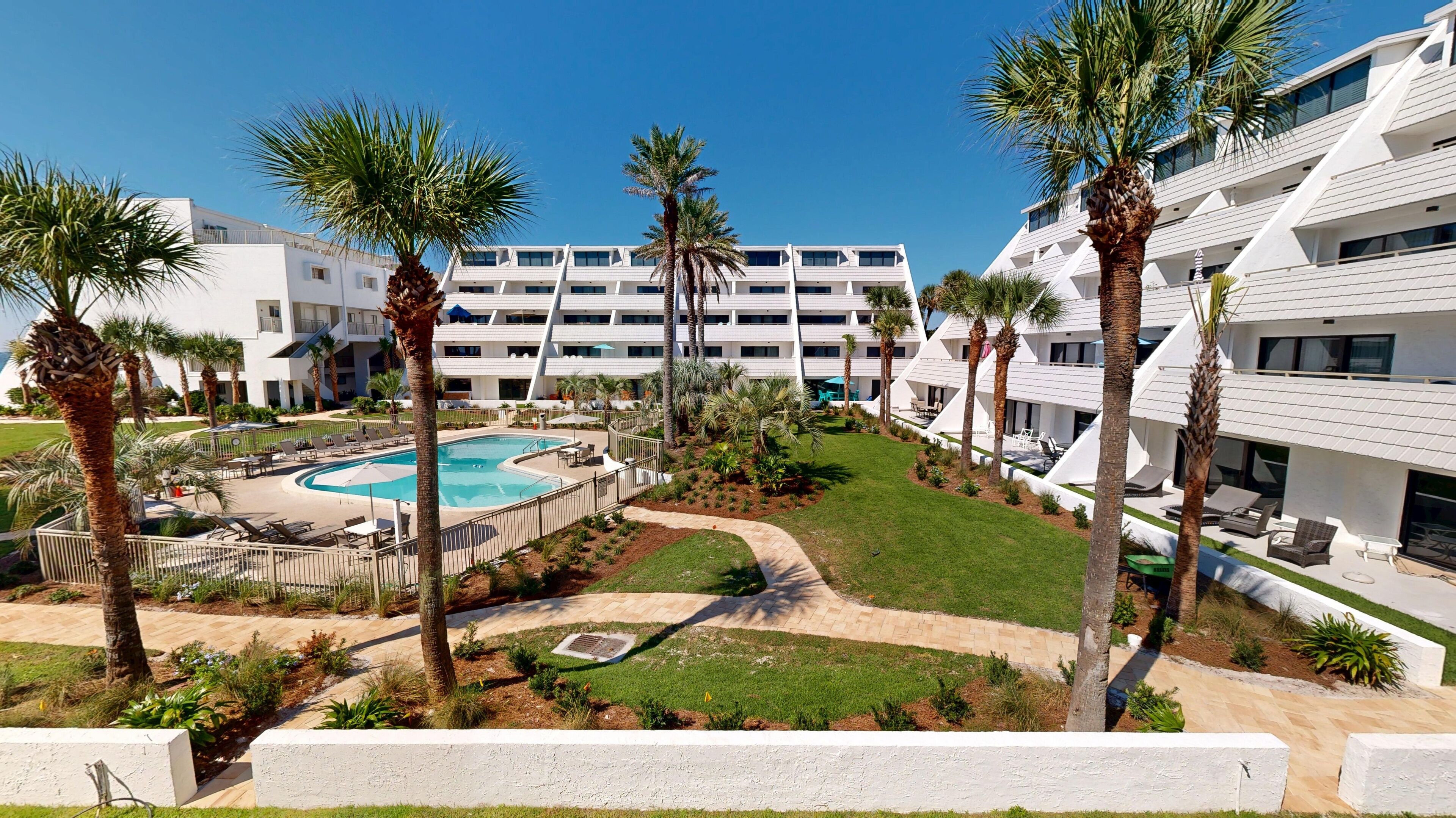 A resort with a pool, palm trees, and modern buildings.