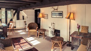 A cozy room with wicker furniture, a plaid table, and a fireplace. - Toad Hall Swilland, a beautiful, 5 bedroom country residence surrounded by Suffolk countryside (Swilland,)