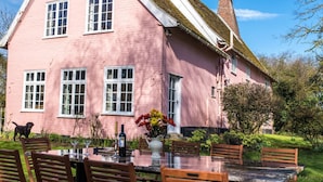 A pink house with a dining area and a dog. - Toad Hall Swilland, a beautiful, 5 bedroom country residence surrounded by Suffolk countryside (Swilland,)