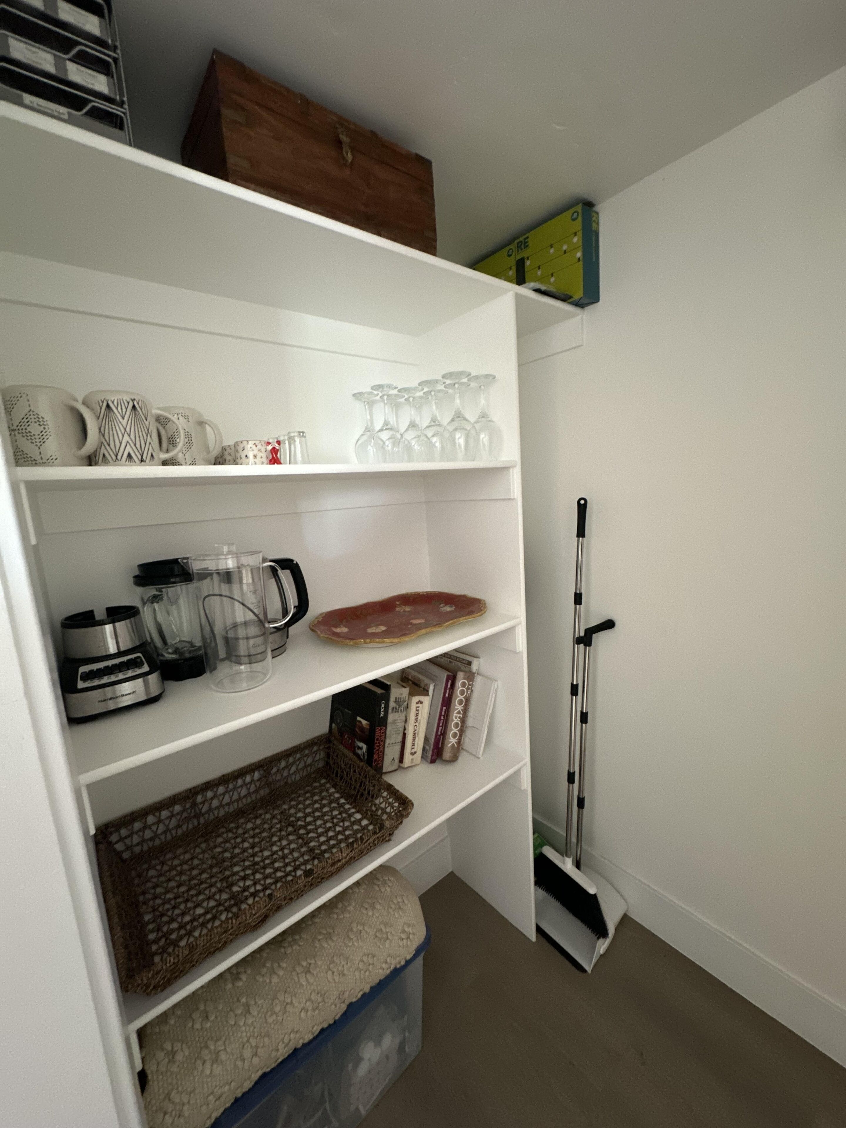 Une étagère blanche contenant des appareils de cuisine, des livres et de la verrerie.