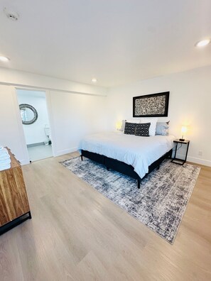 A modern bedroom with a bed, a rug, a nightstand, and a wall art piece. - Lvc0615 - Lake Therapy 3 Bedroom Condo (Zephyr Cove)