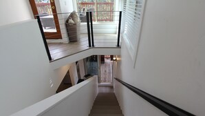 A staircase with a handrail, leading to a balcony with a view of the outside.