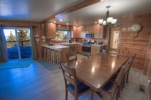 Enjoy meals in this kitchen with a dining table, microwave, oven, and sink, offering a view of the outdoors.