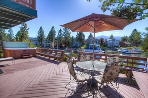 A wooden deck with a hot tub, outdoor seating, and a view of boats on a lake. - Tkh1226 - Emerald Lodge 6 Bedroom Home (South Lake Tahoe)