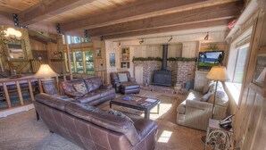 A cozy living room with a sectional sofa, a fireplace, and a television. - Tkh1226 - Emerald Lodge 6 Bedroom Home (South Lake Tahoe)