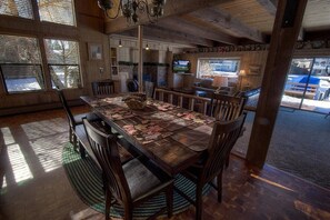 Enjoy meals in this spacious dining area with a large table for six, a mounted TV, and a view of the outside.
