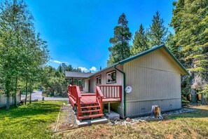 A small, single-story building with a porch and a satellite dish, surrounded by trees and a clear sky. - Coh1261 - Nature's Gem 4 Bedroom Home (South Lake Tahoe)