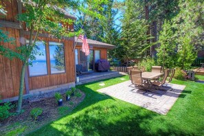 Une maison en bois dotée d’un patio, de mobilier d’extérieur et offrant une vue sur l’eau.