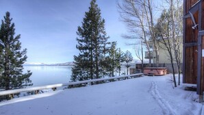 Une terrasse enneigée offrant une vue sur un lac et des montagnes.