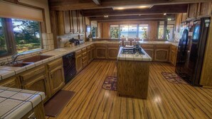 Une cuisine spacieuse avec des meubles en bois, un îlot central et une vue sur l’extérieur.
