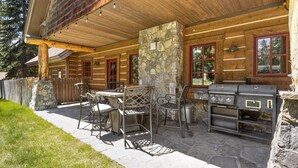 En udendørs terrasse med stenstolper, grill og metalstole.