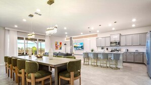 A modern kitchen with grey cabinets, stainless steel appliances, and a central island with bar stools.