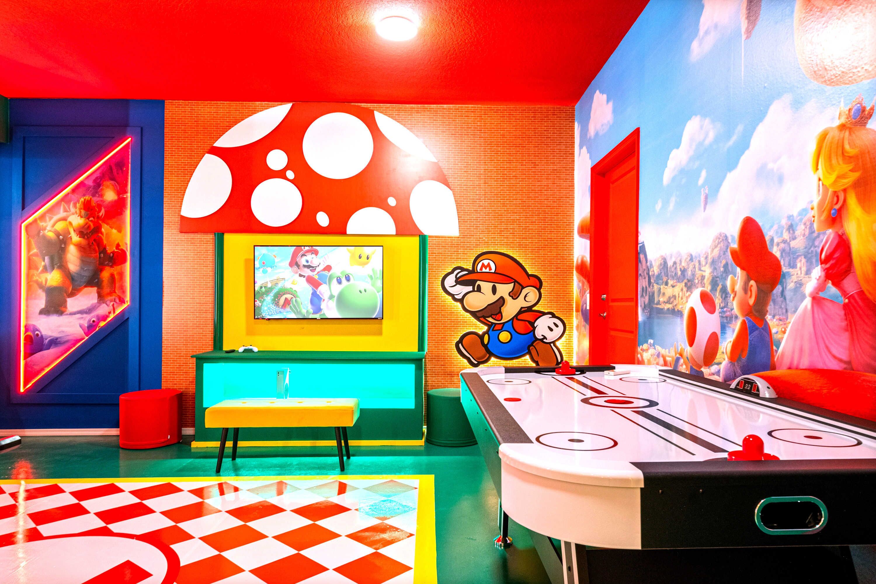 Une pièce aux couleurs vives, avec une table de billard, une fresque murale sur le thème de Nintendo et un banc.