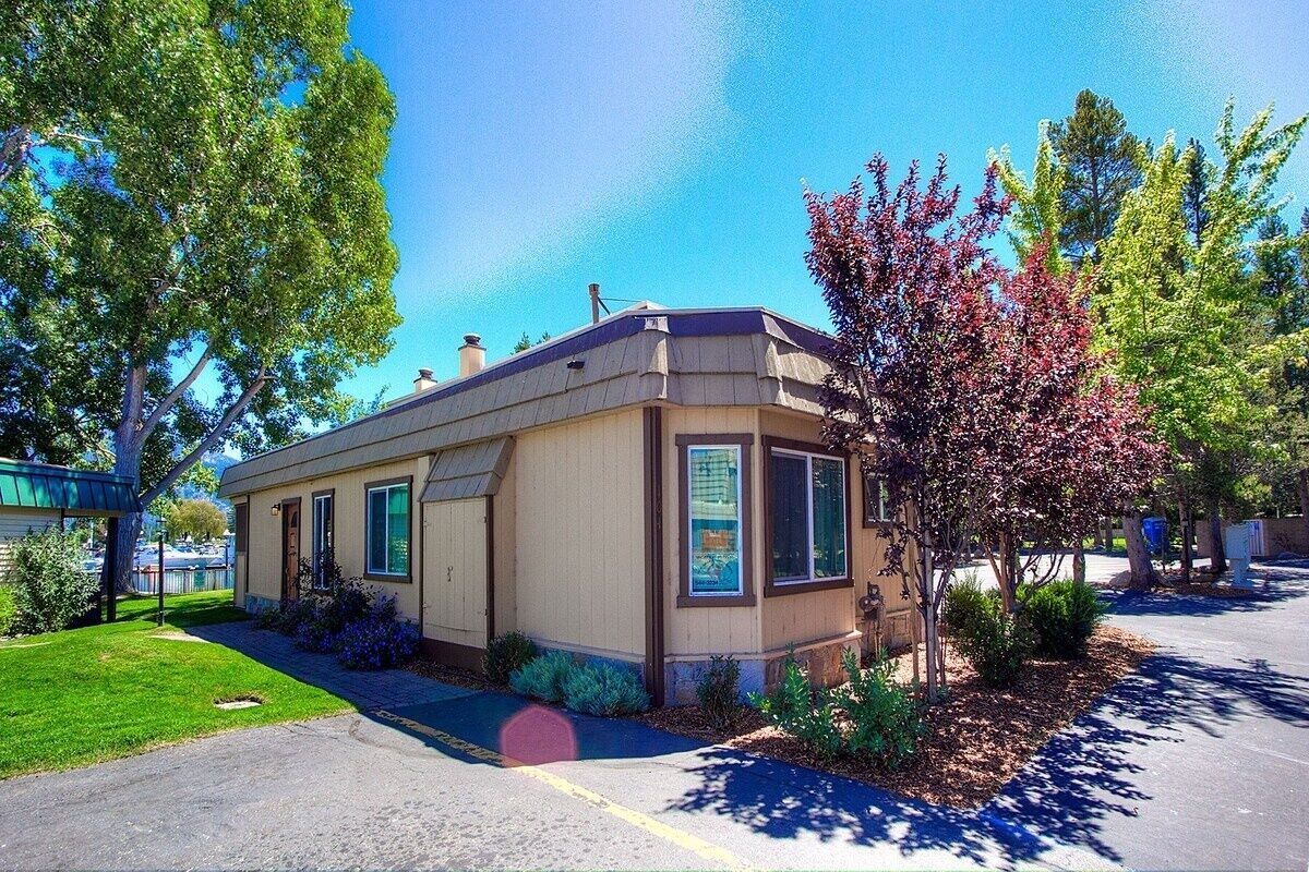 A single-story building with a beige exterior, a small porch, and a well-maintained lawn.