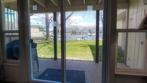 A sliding glass door leading to a covered outdoor area with a view of a grassy yard and mountains in the background. - Tkc0604 - Betty Ann's Place 2 Bedroom Condo (South Lake Tahoe)