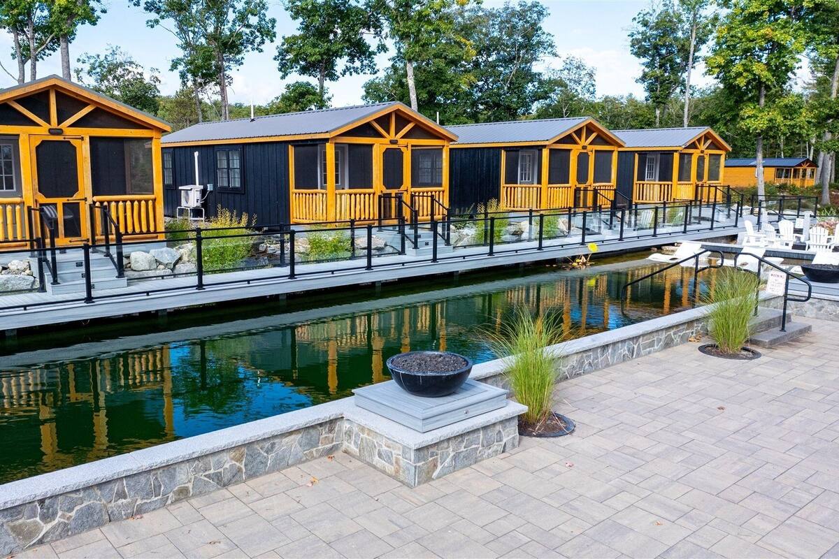 A row of cabins with a stone pathway and a small pond.