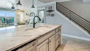 A kitchen with a large island, a built-in dishwasher, and a view to the dining area. - Kontiki Bayfront 103 2 Bedroom Condo (Rockport)