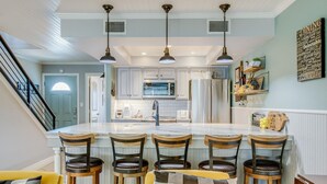 A modern kitchen with a central island, bar stools, and pendant lighting. - Kontiki Bayfront 103 2 Bedroom Condo (Rockport)