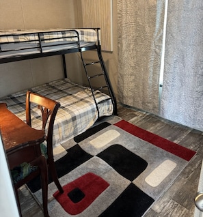 Cozy retreat with a bunk bed, dining table, and chair, set against a textured backdrop.