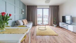 Una sala moderna con sofá, televisor y mesa de comedor con un florero.