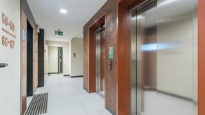 Un pasillo moderno de hotel con un plano de distribución claro, que incluye una zona de recepción, ascensores y señales de salida de emergencia.