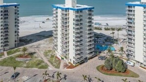 A high-rise hotel with multiple floors, a pool, and a beach view.