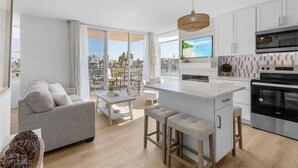 A modern kitchen with a large island, white cabinetry, and a view of the city.