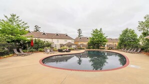 Ein Swimmingpool mit roter Ziegelumrandung, umgeben von Liegestühlen und einer Terrassenfläche.