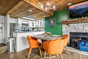 Una cocina moderna con armarios blancos, horno integrado y chimenea de piedra.