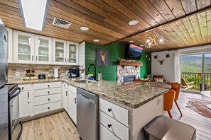 A modern kitchen with white cabinets, granite countertops, and a built-in dishwasher.
