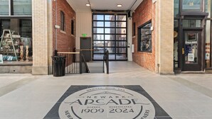The entrance to the Newark Arcade with a clear view of the brick facade and a large glass door. - Local Discounts!-The Revitalized Newark Arcade (Newark)