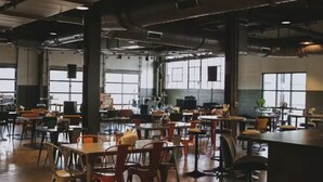 A spacious cafeteria with high ceilings, exposed ductwork, and large windows. Tables and chairs are arranged for dining. - Local Discounts!-The Revitalized Newark Arcade (Newark)