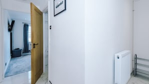 A hallway with a wooden door, a framed picture on the wall, and a radiator. - Cosy 1BR Apt in Manchester with Free Parking (Manchester)