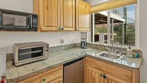Una cocina con armarios de madera, microondas, horno tostador, lavavajillas y ventana con vista a una montaña.