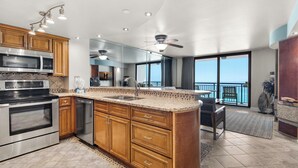 A modern kitchen with granite countertops, stainless steel appliances, wooden cabinets, and a large island.