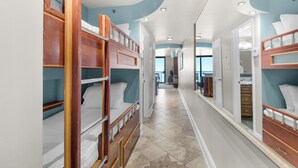 A corridor with bunk beds on the left and a vanity area on the right.