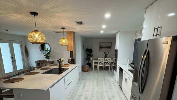A modern kitchen with a central island, stainless steel appliances, and pendant lighting.