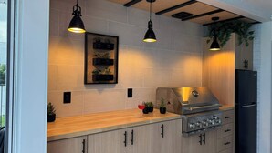 A modern kitchen with wooden cabinets, a stainless steel stove, and pendant lighting.