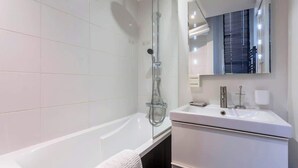 Une salle de bain moderne équipée d’une baignoire, d’une douche, d’un lavabo et d’un miroir.