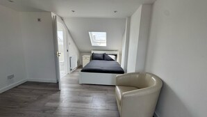 Ein Schlafzimmer mit Bett, Stuhl und Dachfenster.