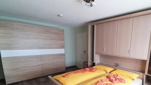 Une chambre à coucher avec un lit, une armoire en bois et un ventilateur de plafond.