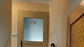 Un escalier avec un mur à texture sur le côté droit et une porte en verre dépoli en haut.