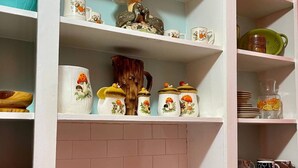 A kitchen with white cabinets, a stainless steel sink, and a coffee maker. - 1BR Coastal Escape (Galveston)
