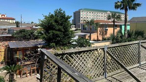 A hotel with a green roof, a wooden deck, and palm trees. - 1BR Coastal Escape (Galveston)