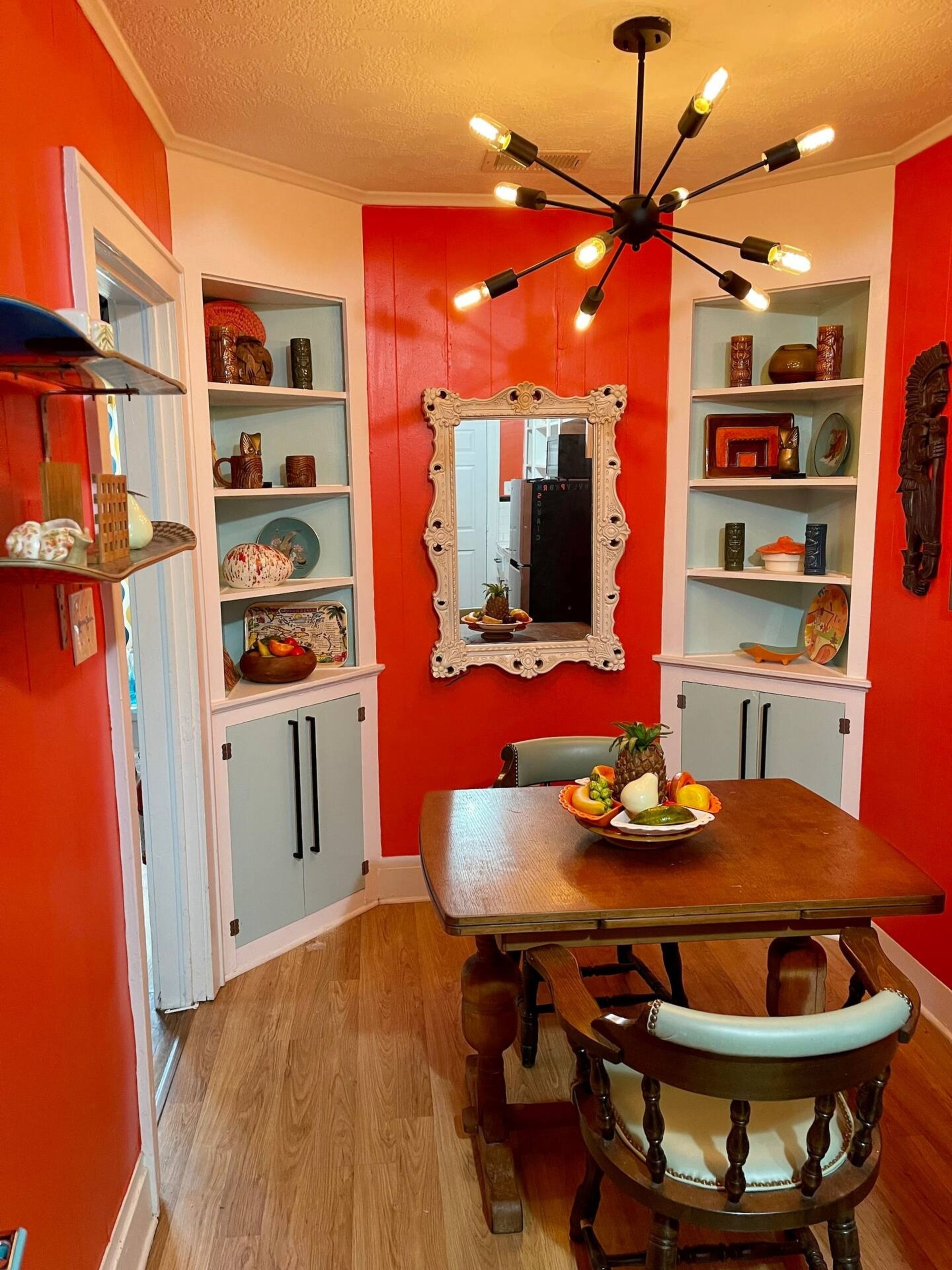 Un coin repas avec une table en bois, des chaises et un miroir au mur.