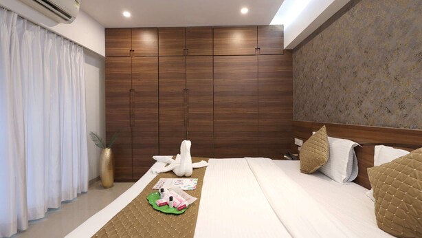 Ein Hotelzimmer mit einem großen Bett, einem Holzschrank, einer Wand mit Dekoration und einem mit Vorhängen versehenen Fenster.
